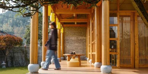 a man walking through a porch with a table at Huangshan Yixian Pumanmanju Hotel in Huangshan