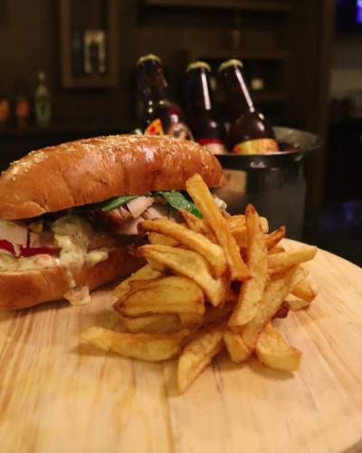 a sandwich and french fries on a wooden cutting board at Hesperia Maracay in Maracay