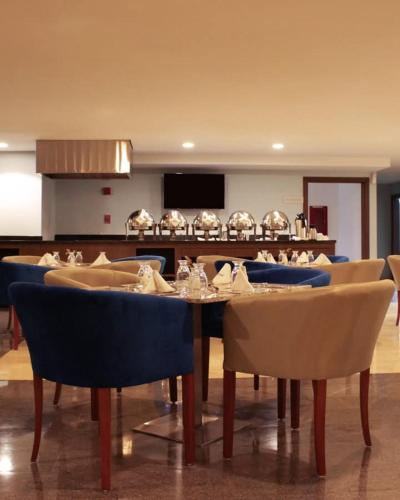 a dining room with a table and blue chairs at Hesperia Maracay in Maracay