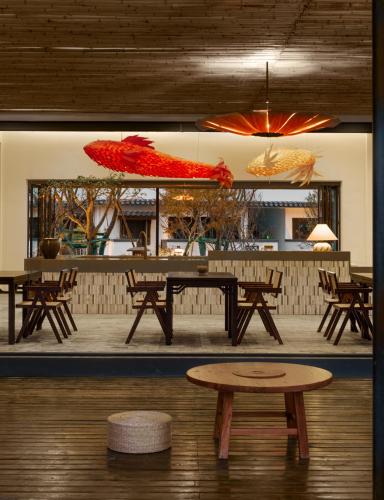 a group of tables and benches in a room with umbrellas at Huangshan Yixian Pumanmanju Hotel in Huangshan