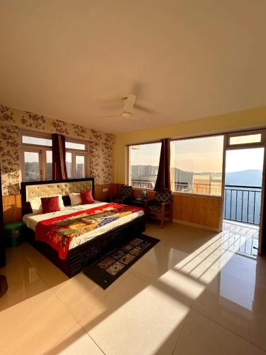 a bedroom with a bed and a balcony with windows at Hotel Shimla hills in Kīar