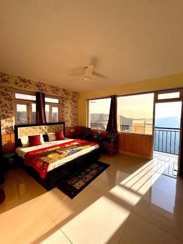 a bedroom with a bed and a balcony with windows at Hotel Shimla hills in Kīar