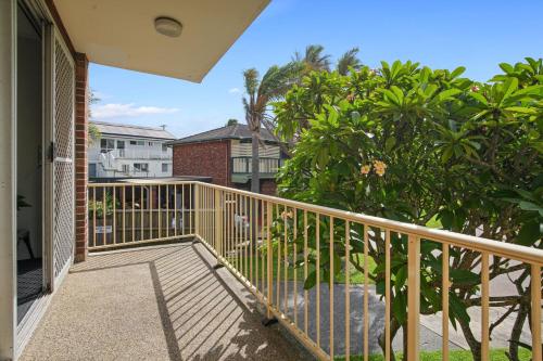 a balcony with a wooden railing and trees and buildings at Cul-de-Sac Cove, Unit 4 in The Entrance