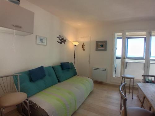 un salon avec un canapé avec des coussins bleus dans l'établissement Studio bord de plage Seignosse, loggia ouest - FR-1-239-1110, à Seignosse