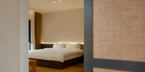 a bedroom with a bed with white sheets and pillows at Huangshan Yixian Pumanmanju Hotel in Huangshan