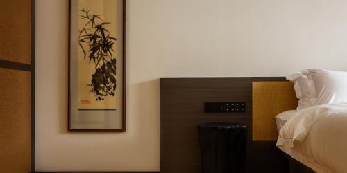a bedroom with a bed and a picture on the wall at Huangshan Yixian Pumanmanju Hotel in Huangshan