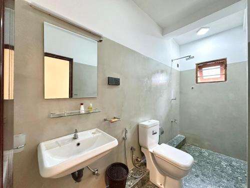 a bathroom with a sink and a toilet and a mirror at Tobby Home Stay in Ahangama