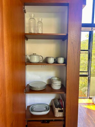 a wooden cabinet with plates and dishes in it at NATURAVE HOME - Tiny house with mountain view in Monteverde Costa Rica