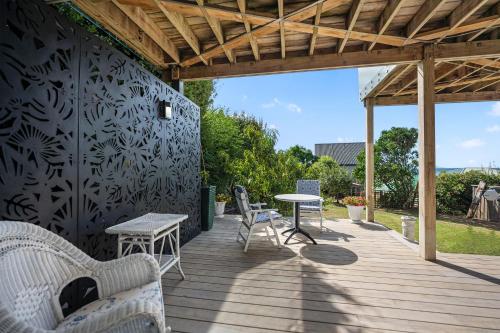 a wooden deck with a table and chairs on it at Pacific Ocean Breezes in Whangaparaoa