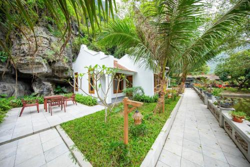 a garden with tables and chairs and palm trees at Hang Mua Ecolodge in Ninh Binh