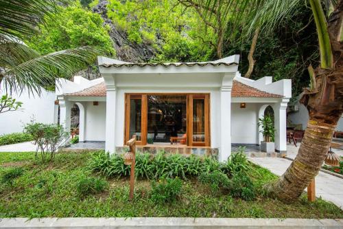 a small white house with a palm tree at Hang Mua Ecolodge in Ninh Binh