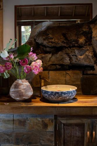 a table with a bowl and a vase with flowers at Hang Mua Ecolodge in Ninh Binh