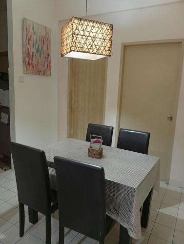 a dining room table with chairs and a light fixture at Teratak RIZQ Kota Samarahan in Kota Samarahan