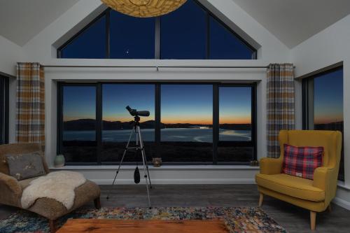 a camera in a living room with a view of the sunset at Modern and Dog Friendly Holiday Home with Sea Loch Views in Breaclete