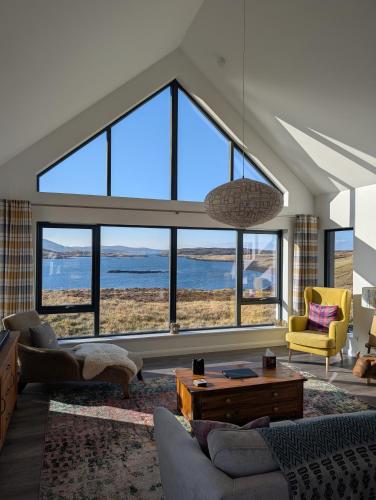 a living room with a large group of windows at Modern and Dog Friendly Holiday Home with Sea Loch Views in Breaclete