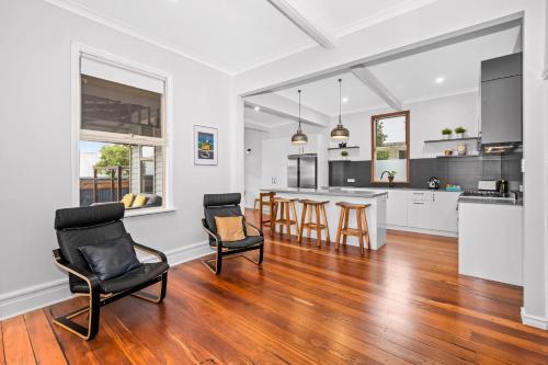 an open kitchen and living room with wooden floors and chairs at Albany Beachside Accommodation in Albany
