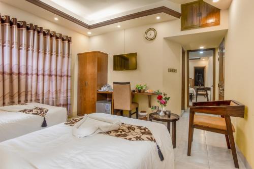a hotel room with two beds and a desk at Memento Residence in Dhaka
