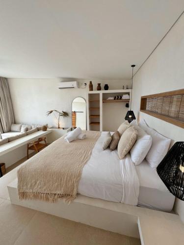 a large white bedroom with a large bed and a desk at Ecstatic Villa, heart of Uluwatu in Uluwatu