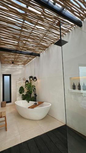 a bathroom with a large tub and a plant at Ecstatic Villa, heart of Uluwatu in Uluwatu