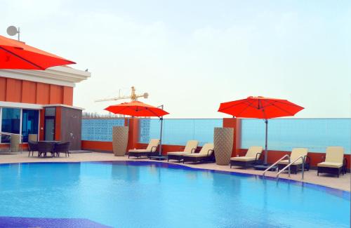 a large swimming pool with chairs and umbrellas at Ramada by Wyndham Manama City Centre in Manama