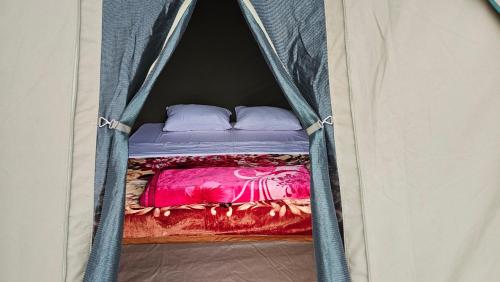 a small bed in a tent with two pillows at Twin Lakes Eco Lodge Campsite in Rubirizi