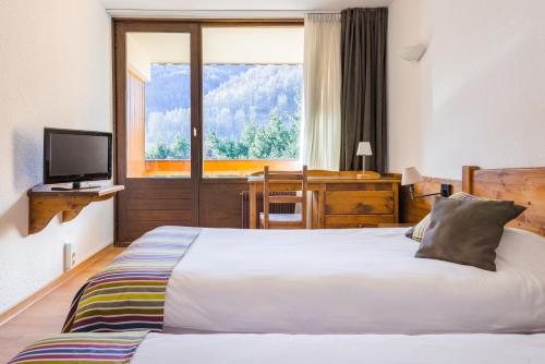 a hotel room with a bed and a television at Hôtel Plein Sud et piscine *** in Saint-Chaffrey