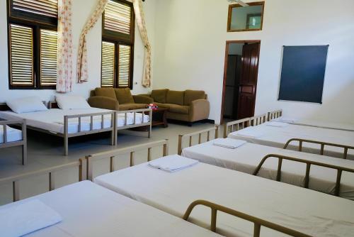 a room with four beds and a couch and a tv at Amaluna Resorts in Negombo