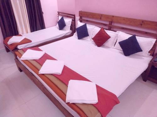two beds in a room with white sheets and pillows at Samant Beach Resort in Malvan