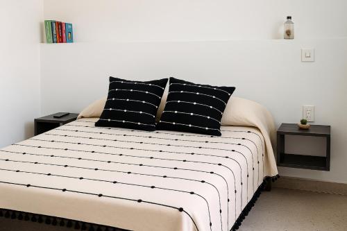a bed with black and white sheets and pillows at Casa Monarca in Oaxaca City