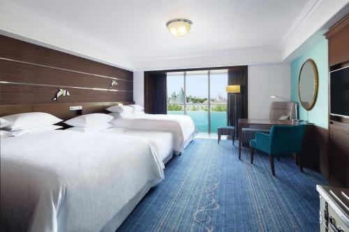 a hotel room with two beds and a desk at Sheraton Grande Tokyo Bay Hotel in Urayasu