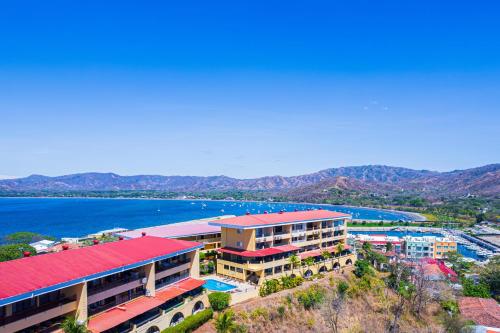 a building with a red roof next to a body of water at Paraiso Presidential 20 -Ocean View Penthouse And Digital Nomad Haven in Playa Flamingo