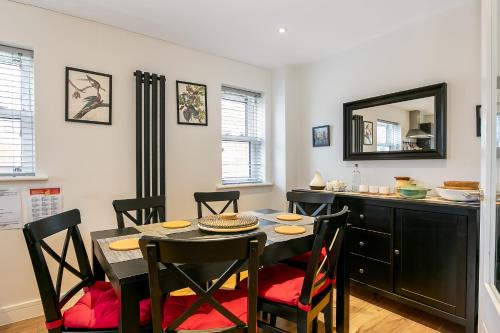 a dining room with a table and chairs and a mirror at Cosy 3 Bedroom Home Next to Bicester Village! in Bicester