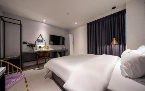 a bedroom with a large white bed and a desk at Wonju Bellino Hotel in Wonju