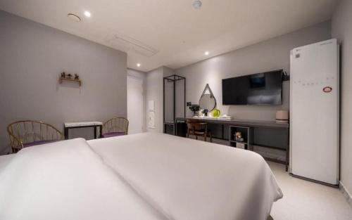 a bedroom with a large white bed and a kitchen at Wonju Bellino Hotel in Wonju