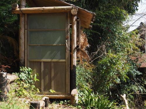 a small wooden door in the middle of a garden at 六弥苑 in Matsuzaki