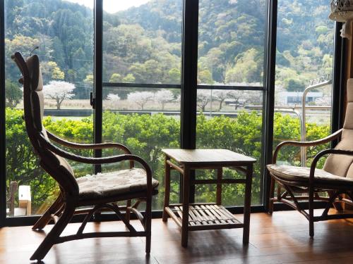 two chairs and a table in front of a large window at 六弥苑 in Matsuzaki