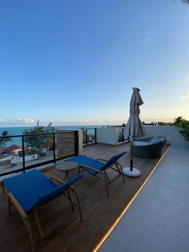 a deck with two chairs and an umbrella at Flat na beira-mar de Tamandaré in Tamandaré
