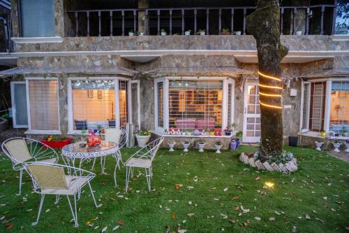 a patio with chairs and a table and a tree at Woodburry Mansion, Cozy Nainital Homestay in Nainital