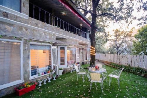 a patio with chairs and a table and a tree at Woodburry Mansion, Cozy Nainital Homestay in Nainital