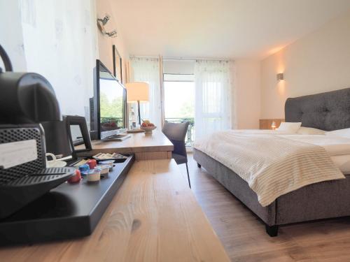 a bedroom with a bed and a desk with a television at Landhotel Waldheim in Pliezhausen