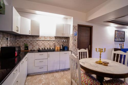 a kitchen with white cabinets and a table in a room at Woodburry Mansion, Cozy Nainital Homestay in Nainital