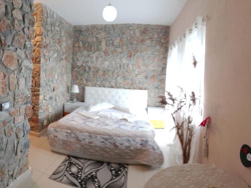 a bedroom with a bed and a stone wall at Hotel Bar Restaurant Stone Dream in Udënisht