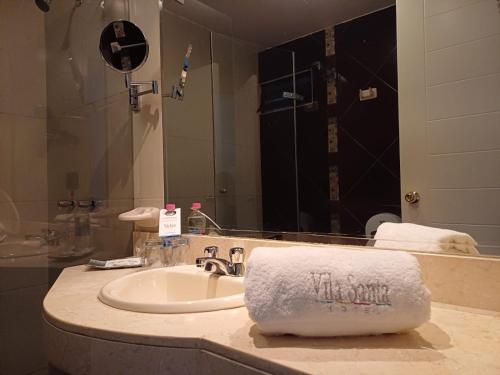 a bathroom with a sink and a mirror and a towel at Hotel Vila Santa in Lima