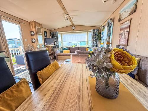 a living room with a table with a vase of flowers at Lovely 6 Berth Caravan With Decking To The Side In Heacham Ref 21040E in Heacham