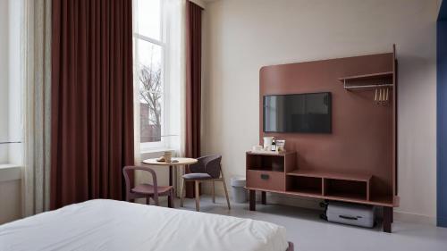 a hotel room with a bed and a table and a tv at Conscious Hotel Oudegracht in Utrecht