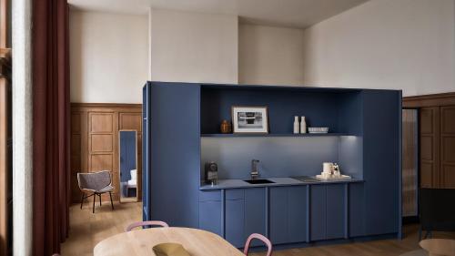 a kitchen with a blue wall and a table at Conscious Hotel Oudegracht in Utrecht