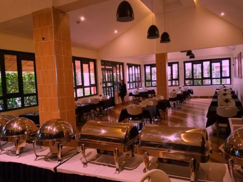 a restaurant with tables and chairs in a room with windows at Lukenya Alkebu Resort in Nairobi