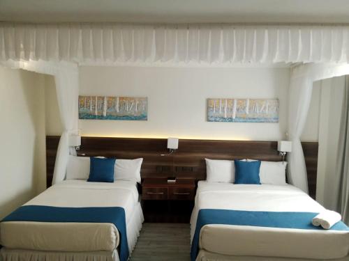 two beds with blue and white sheets in a room at Lukenya Alkebu Resort in Nairobi