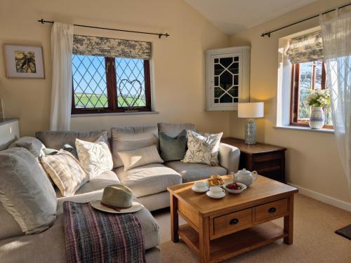 a living room with a couch and a table at Lovely Little Garden Cottage, Tamar Valley, Cornwall in Stoke Climsland
