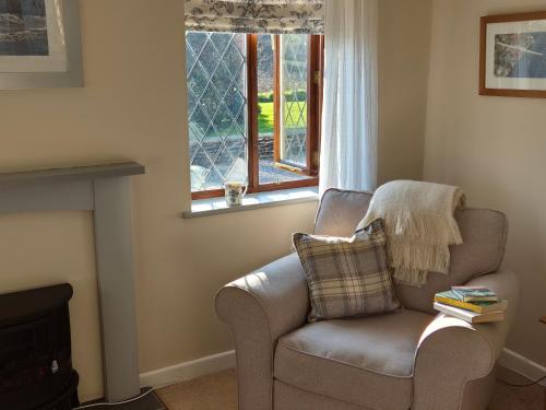 a living room with a chair and a window at Lovely Little Garden Cottage, Tamar Valley, Cornwall in Stoke Climsland